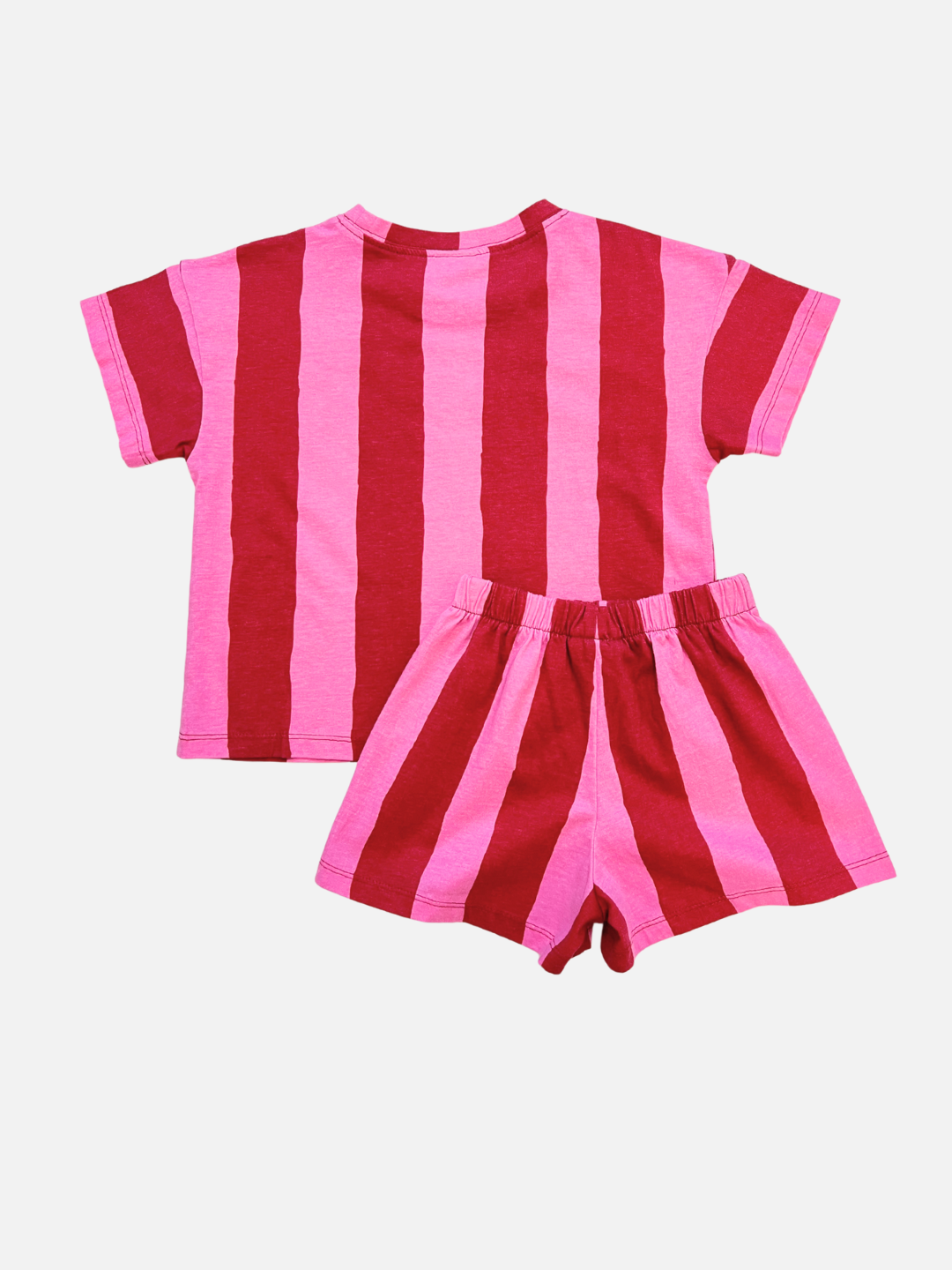 The UMBRELLA STRIPE SHORT SET is a unisex kids' outfit with a short-sleeved shirt and shorts in bold red and pink vertical stripes, made from organic cotton and shown on a white background.