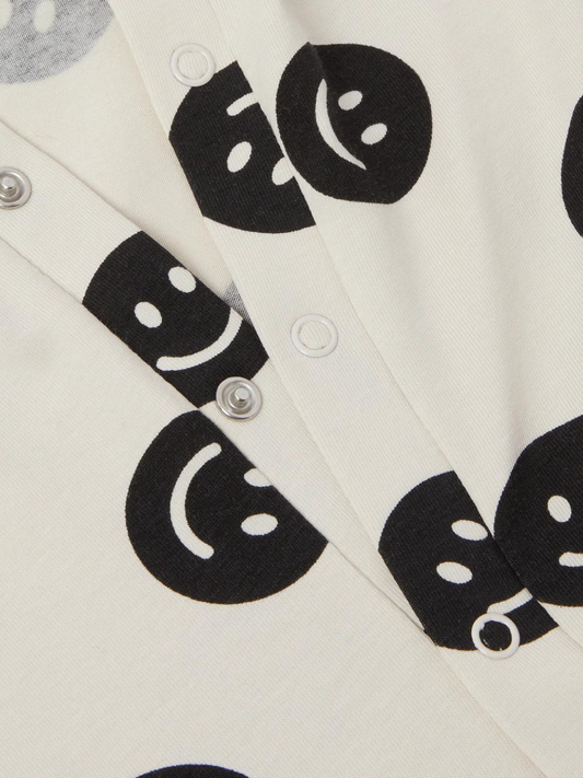 Second image of A front view of the cream colored, long sleeve, and full pant sleepsuit with a black smiley face pattern.