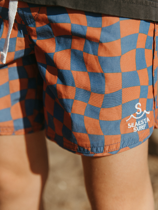 Second image of A front view of kid's Wavy Checks Boardshort. The image displays a front tie and Saesta Surf logo on the left side. 