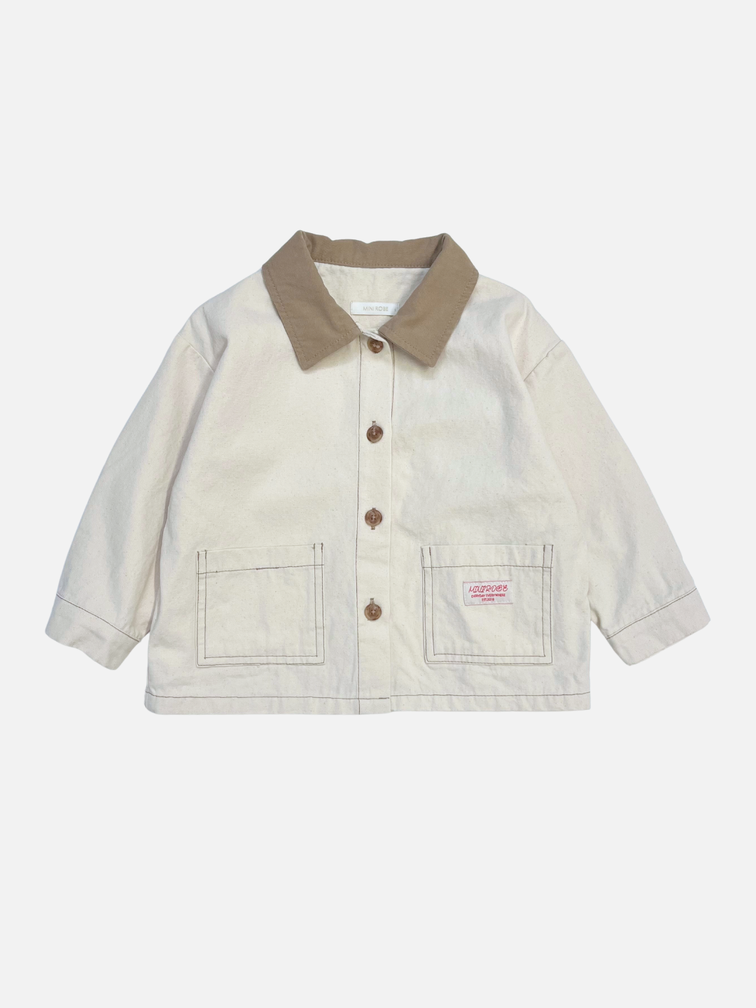 Ecru | The MINI WORKWEAR JACKET in ecru features a brown collar, brown buttons, two front pockets, and a small pink label on the right pocket, shown against a plain white background.