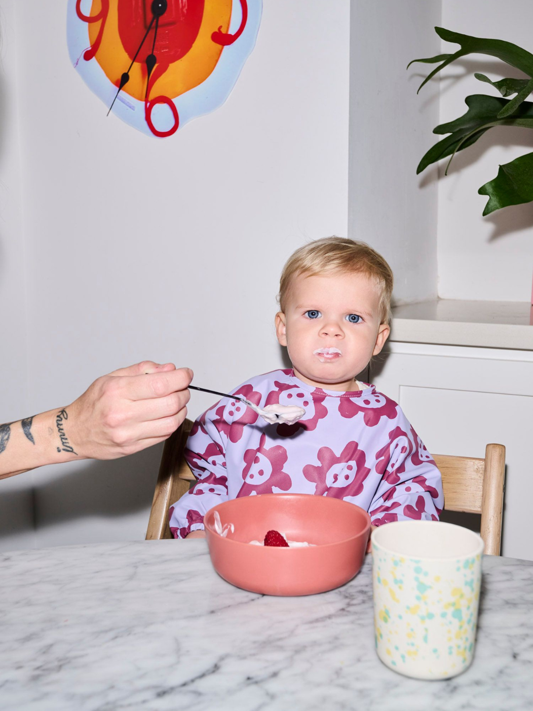 Violet Sunflowers | A child wearing the long sleeve lavender colored bib with dark purple sunflowers and a front pocket.