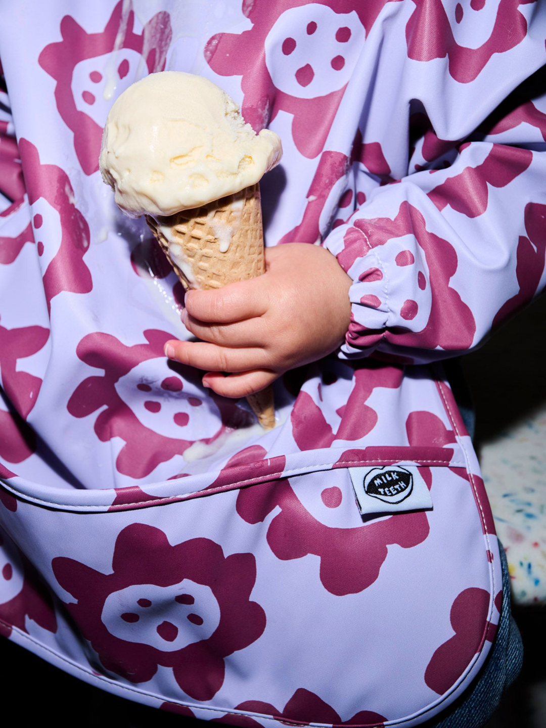 Violet Sunflowers | A zoomed in image of the long sleeve lavender colored bib with dark purple sunflowers and a front pocket.