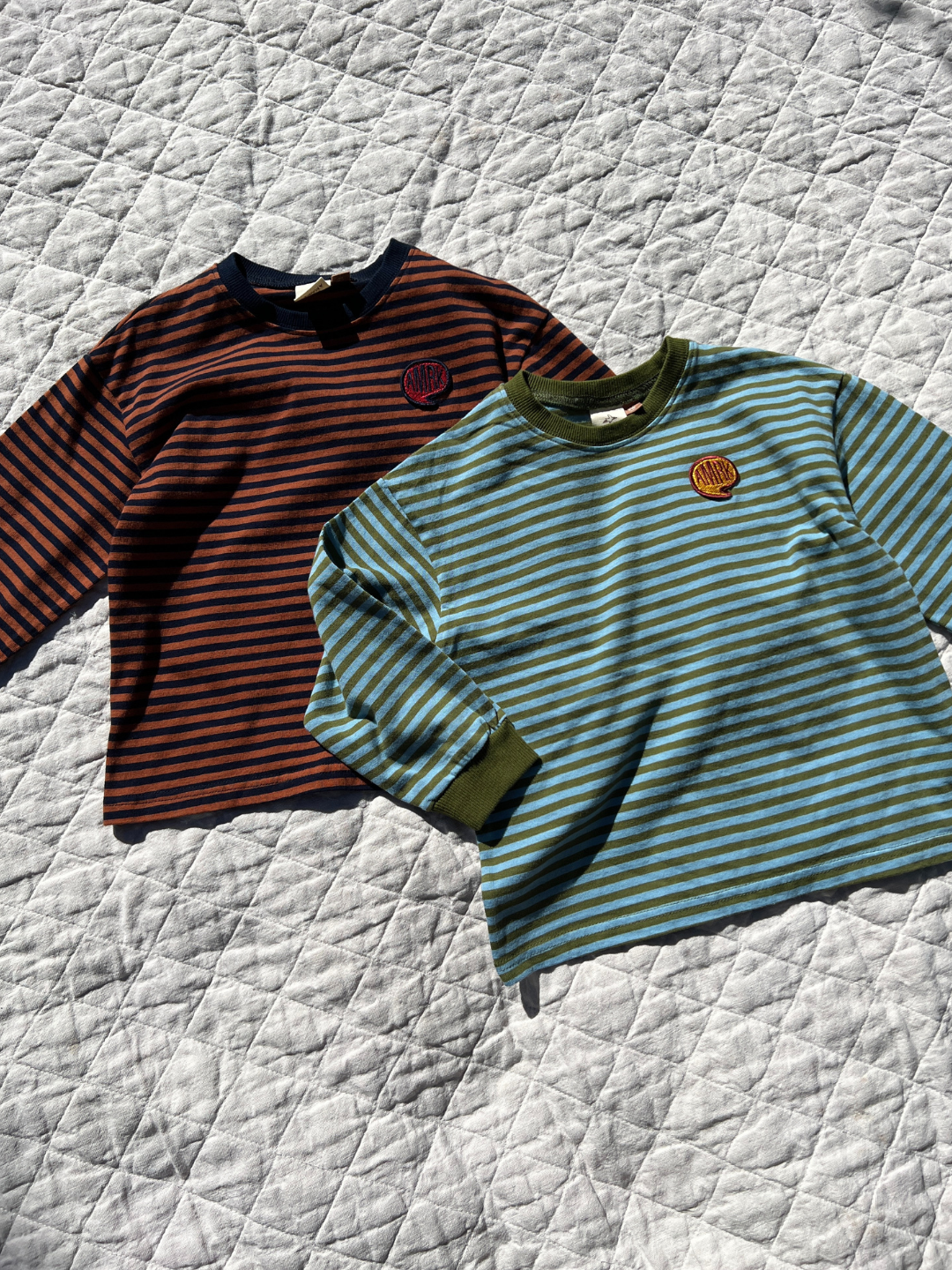 Sky/Olive | Comma Striped Longsleeve in Sky/Olive and Rust/Navy laid on blankets