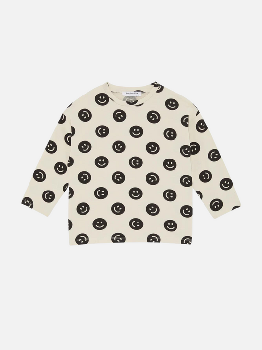 Image of A front view of the cream colored, long sleeve shirt with a black smiley face pattern.