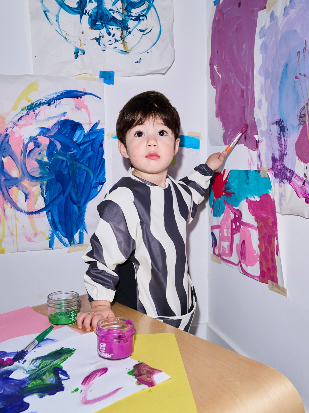 Black Waves | A child wearing the long sleeve black and white wavy bib and a front pocket.