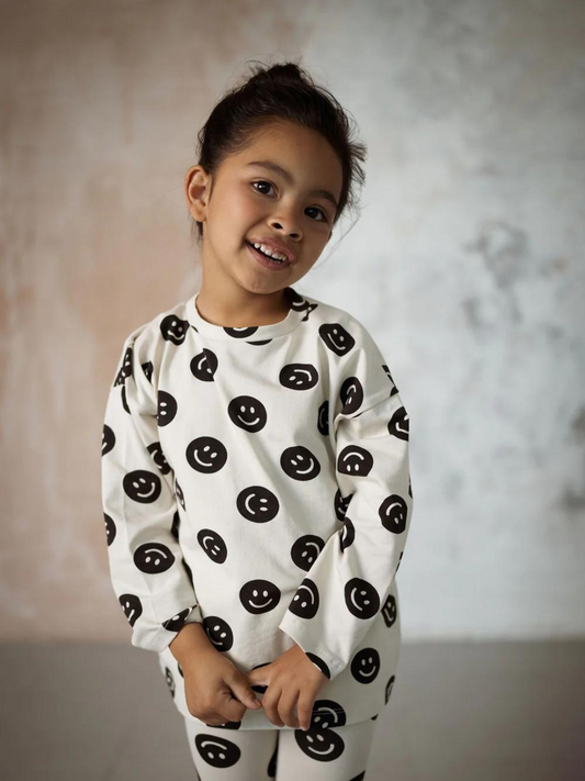 Second image of A front view of the cream colored, long sleeve shirt with a black smiley face pattern.