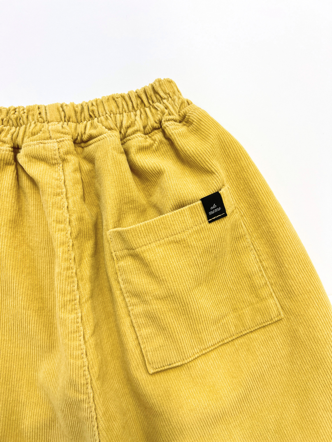 The CORDUROY PANEL PANT is a yellow cotton corduroy pant from a Korean kids brand with an elastic waistband, patch pocket, and small black label—ideal comfy Fall wear.