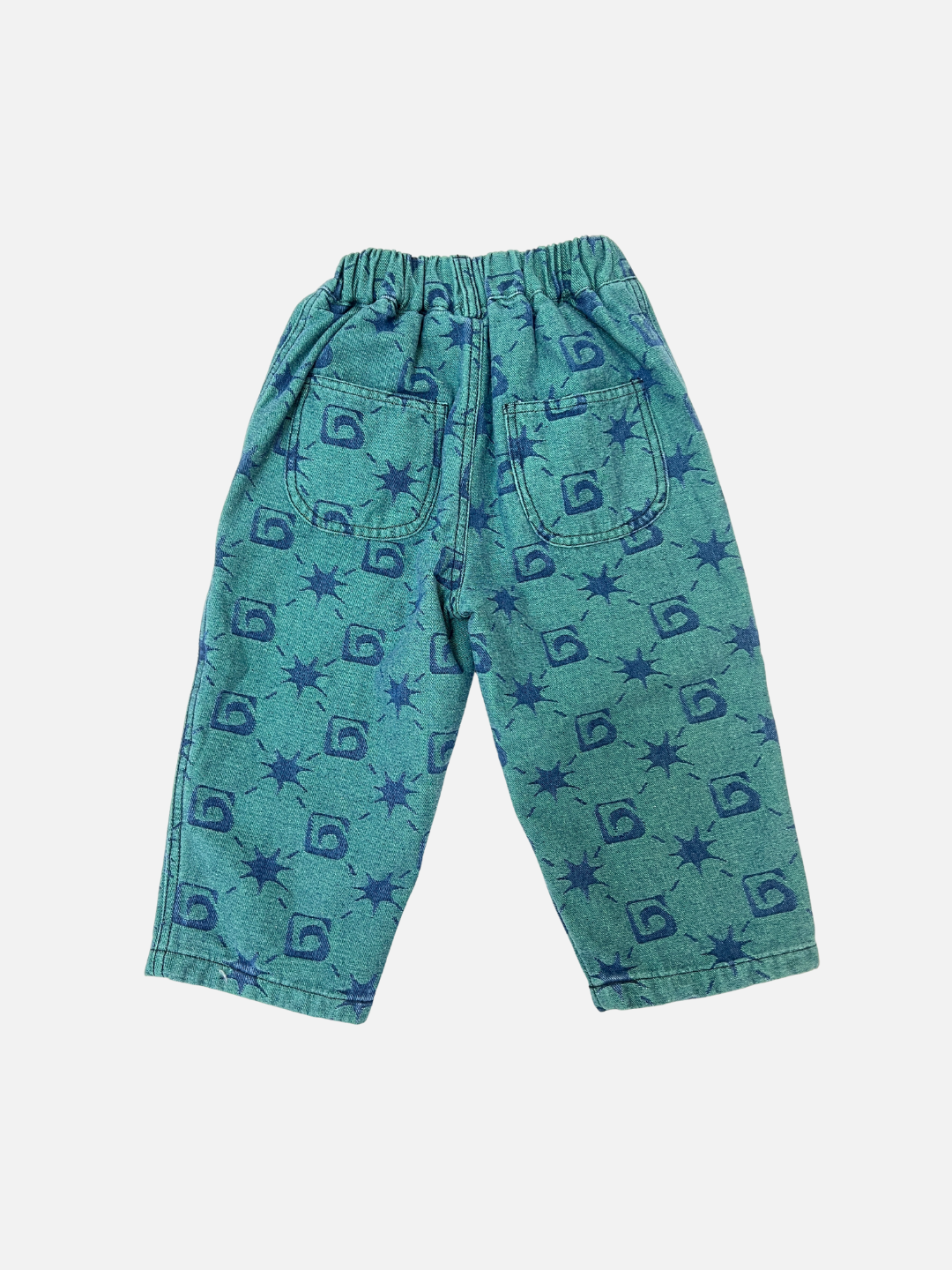 TRELLIS JEANS from the Milk Teeth collection are green children's pants with an elastic waistband, side pockets, and a blue abstract square and star pattern—ideal for a relaxed, jeans-inspired style.