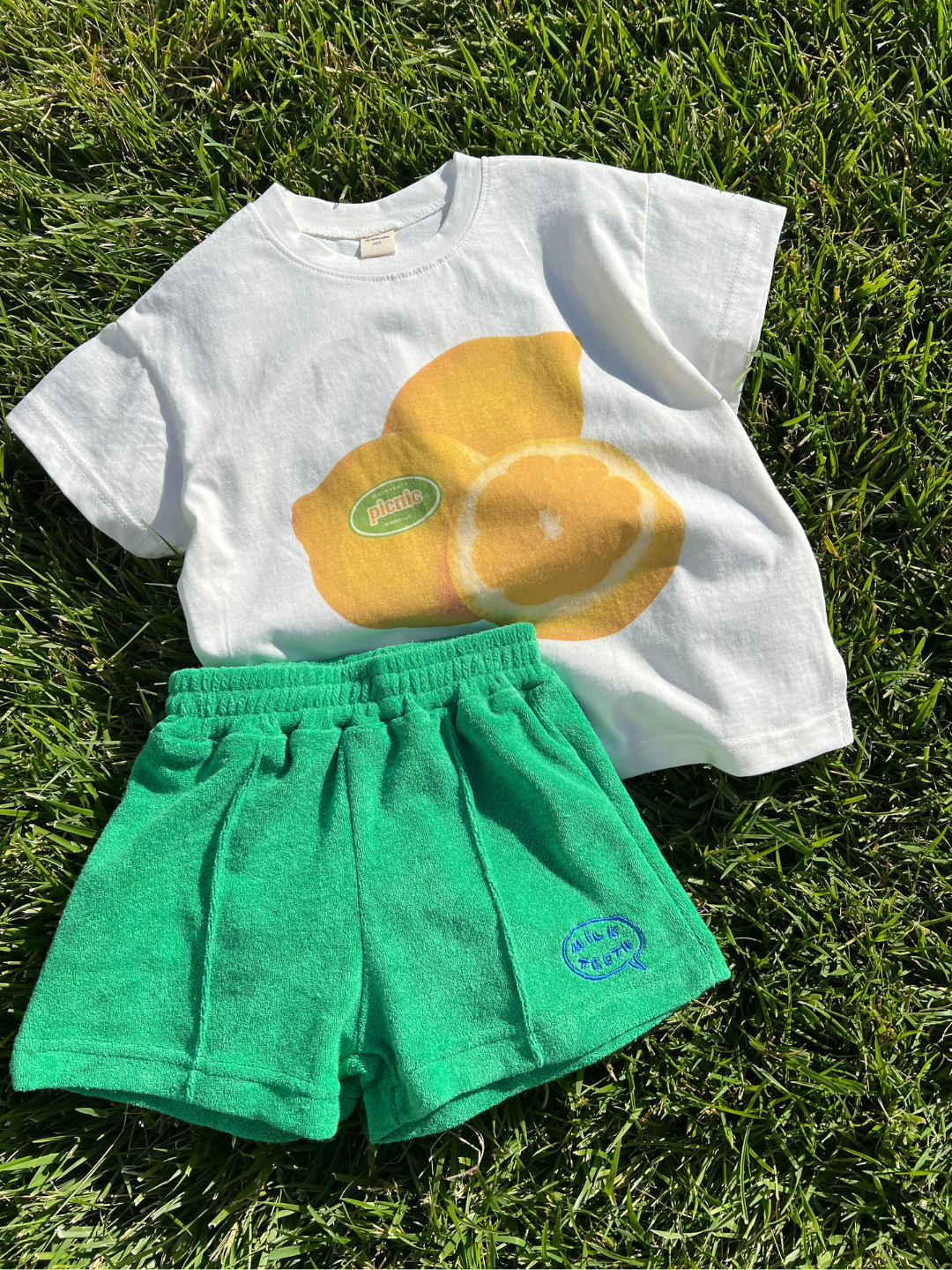Green shorts matched with the lemon tee laid on the grass