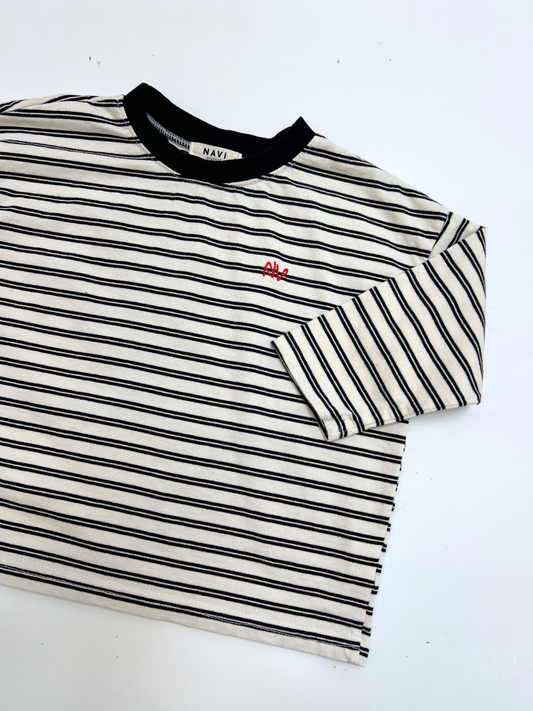 Second image of White | The CANOE LONGSLEEVE TEE in white features black and white stripes, a black collar, and a small red embroidered design on the left chest.