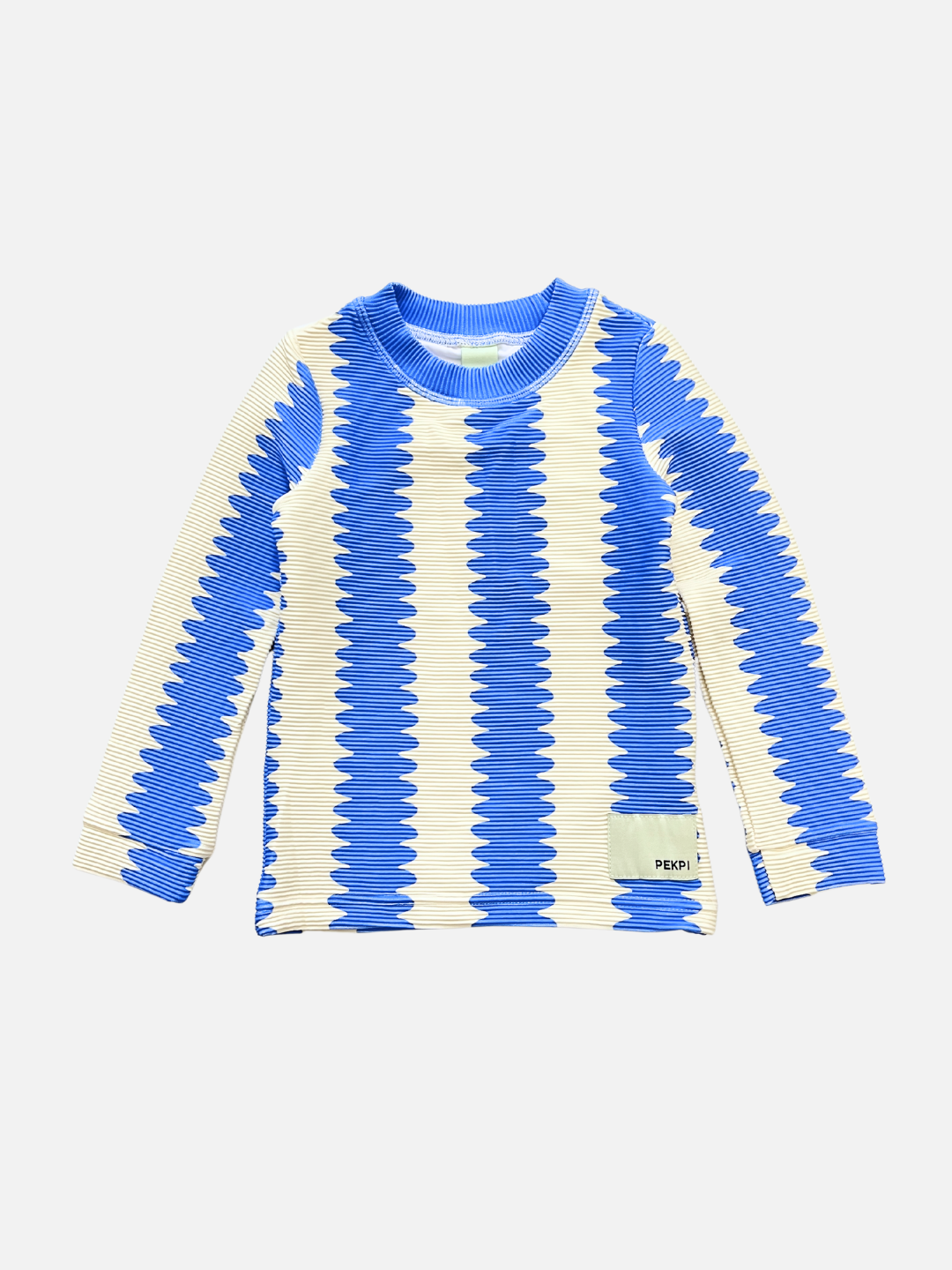 The KIDS RASHIE TOP features a blue and cream zigzag design, ribbed collar and cuffs, and is made from ribbed recycled fabric. A small front label adds detail. Offers UPF 50+ UV protection for active outdoor days.