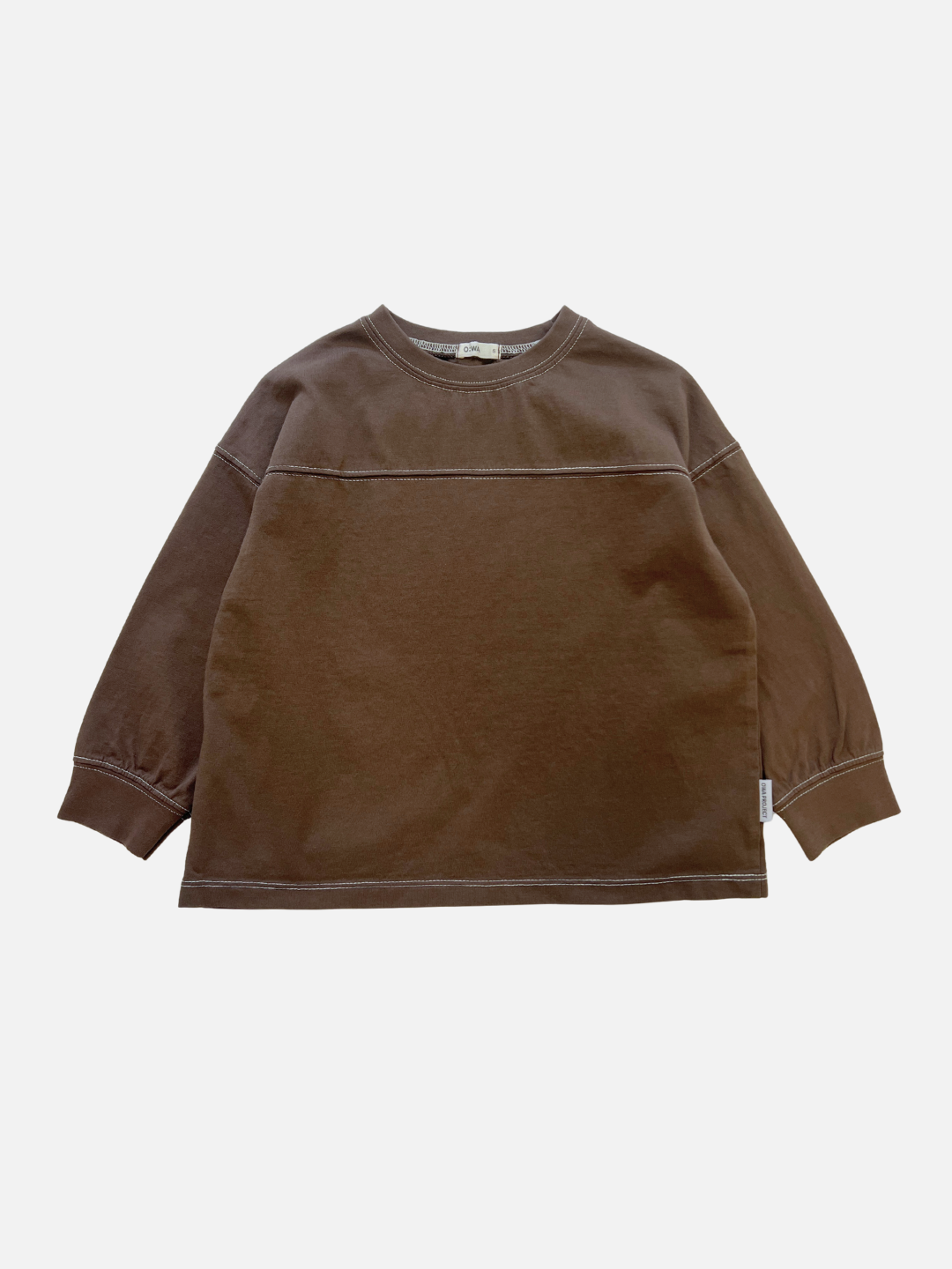 Brown | The BASIC STITCH TEE in brown is a long-sleeve crewneck with a horizontal chest seam and white stitching, displayed flat on a white background.