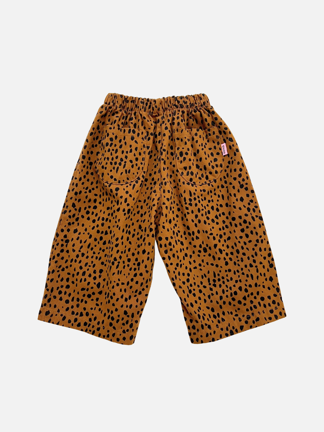 Brown | MINI CHEETAH SPOT PANTS: Wide-legged cotton twill pants with an elastic waistband, brown base, and black spots. Features two back pockets. A stylish unisex kids pick, shown from the back.