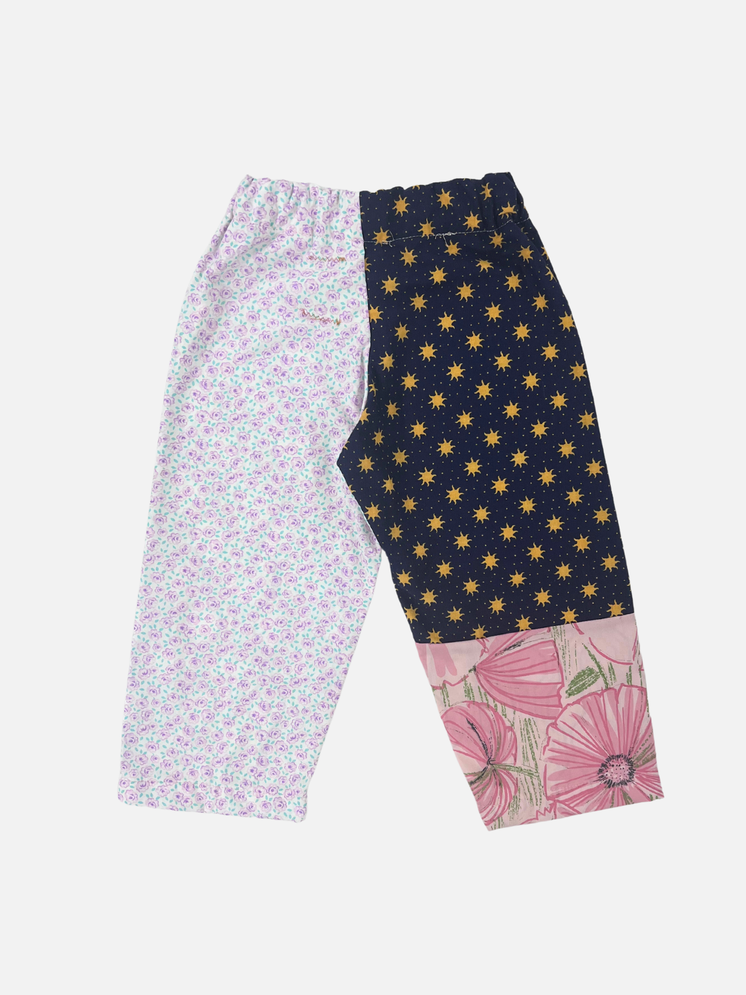 Back view of kid's patchwork pant. Left leg - all over sun print + hibiscus. Right Leg - little violet flowers.