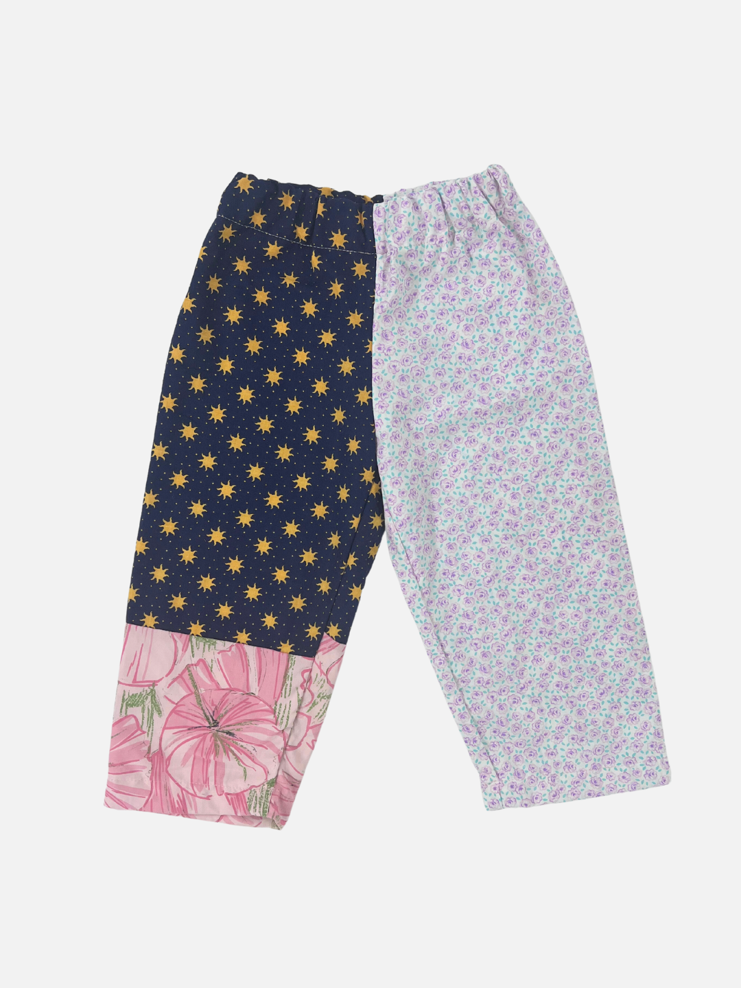 Front view of kid's patchwork pant. Left leg - all over sun print + hibiscus. Right Leg - little violet flowers.