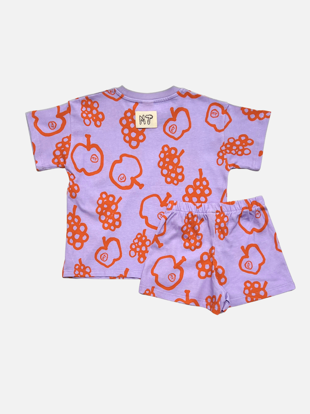 The FRUIT STAND SHORT SET is a light purple kids’ matching set with bright orange apple and grape prints, made from organic cotton—ideal for playful days.
