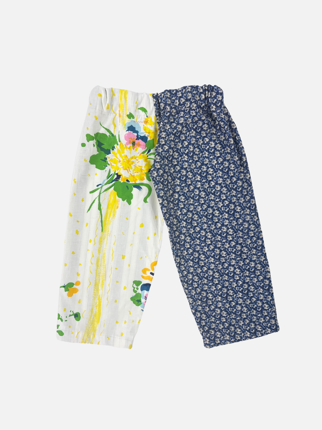 Front view of kid's patchwork pant. Left leg - white flower on navy. Right Leg - yellow splashes and flowers.