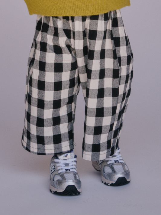 Second image of Black + White | GINGHAM BABY PANTS: Toddler cotton pants with a black and white checkered pattern and an elastic waistband, laid flat on a white background.