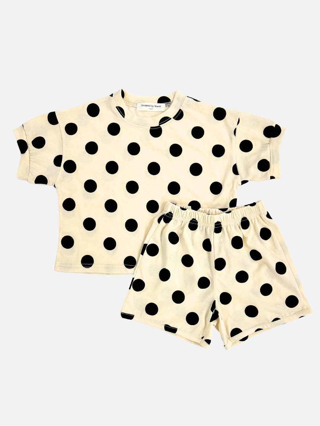 A kids' tee shirt and shorts set in a pattern of black dots on an ecru background