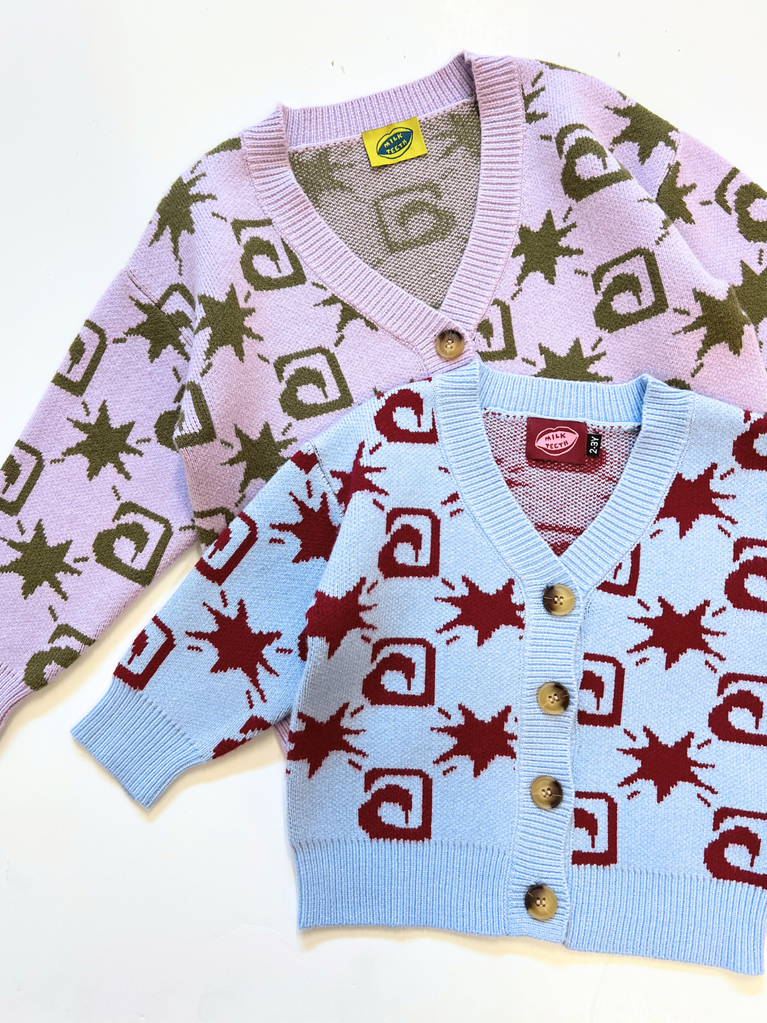 Sky | Two TRELLIS CARDIGAN knit cardigans—one lavender with green patterns, one light blue with red patterns—both featuring brown buttons, are laid flat on a white surface.