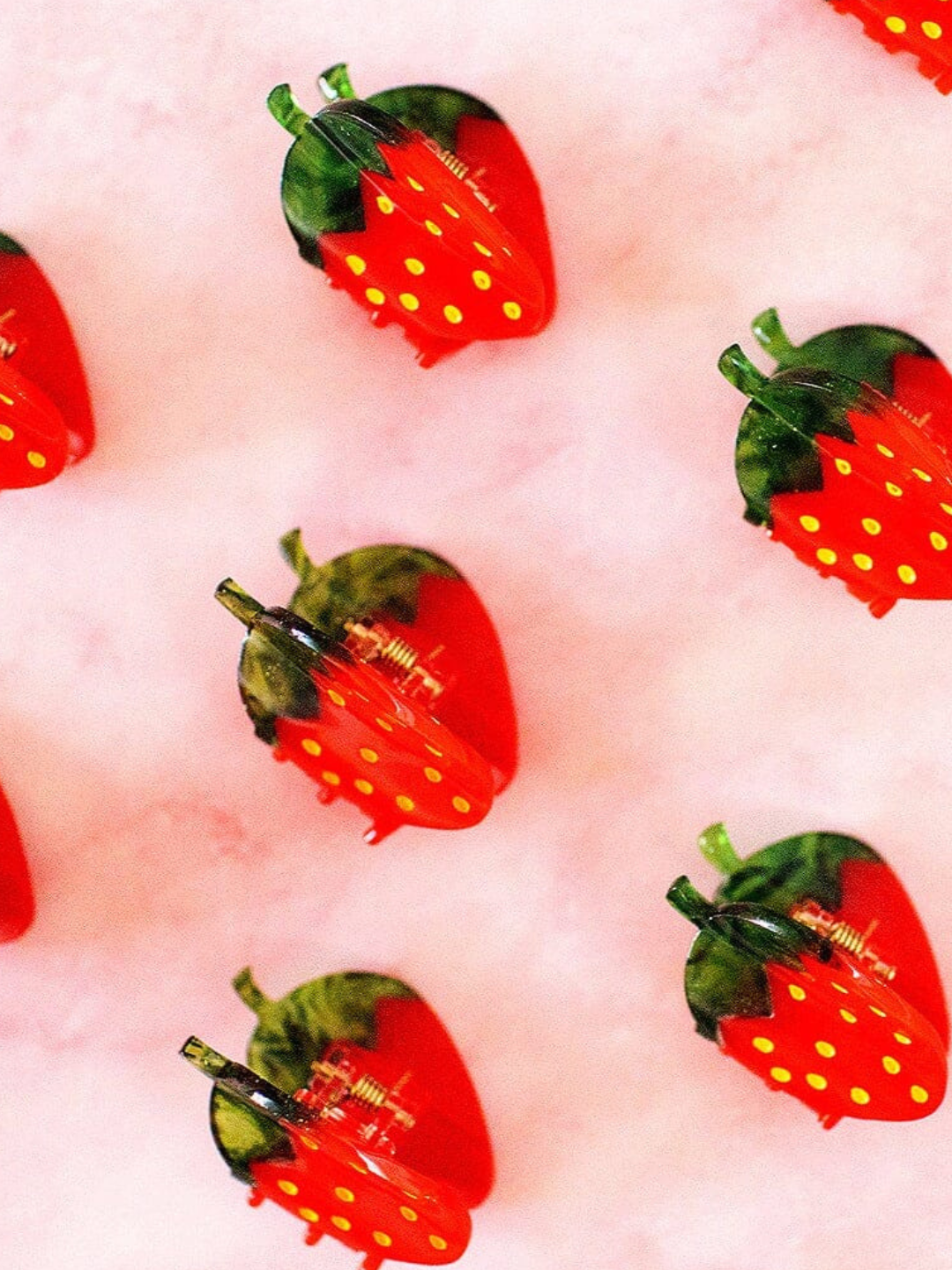 Multiple strawberry clips laid on pink marble