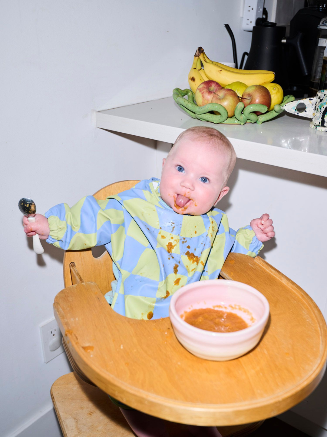 Green Checkers | A baby wearing the long sleeve light green and blue wavy checked bib with a front pocket.