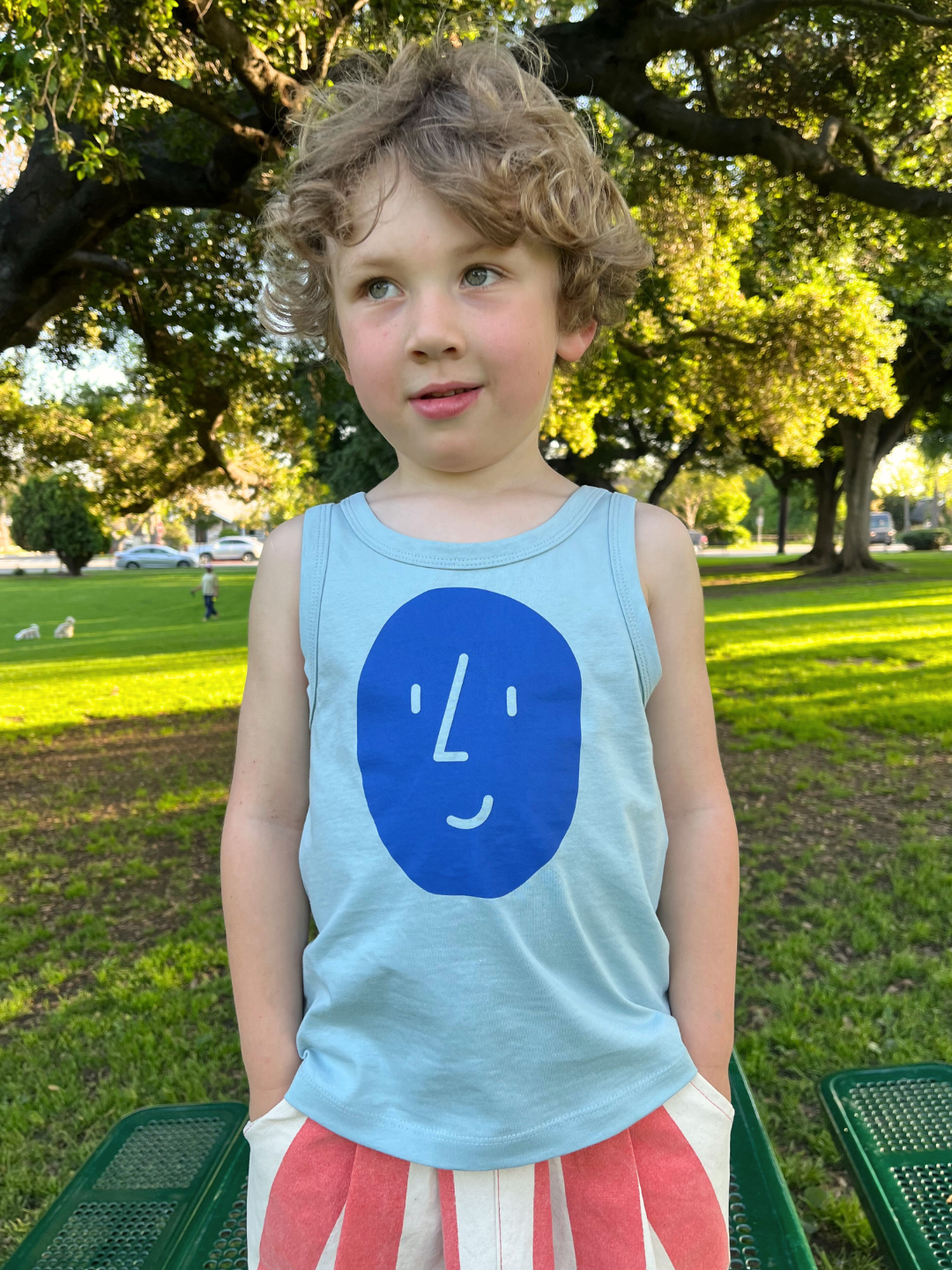 A child is wearing the Potato Face tank top with red striped pants