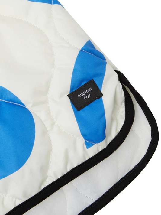 Second image of A front view of the white quilted coat with a hood and zipper closure with an abstract blue shape pattern.