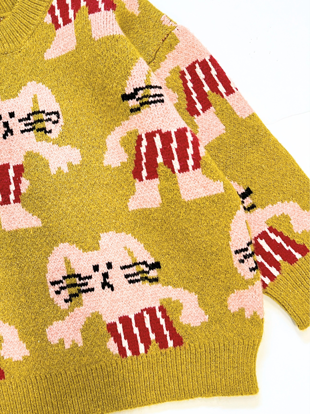 Chartreuse | The MAX SWEATER is a yellow knit with a repeating pattern of stylized pink and red cartoon figures wearing striped shorts, set against a solid background.