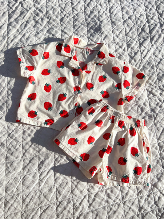 Second image of A front view of the baby Berry Season Set. Classic all over strawberry print, this set includes a button up top and shorts in ivory. The top features an oversized and boxy fit.