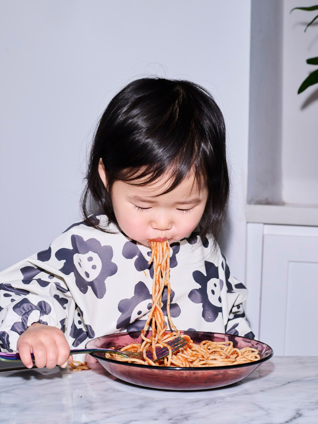 Black Sunflowers | A child wearing the long sleeve cream colored bib with black sunflowers and a front pocket.