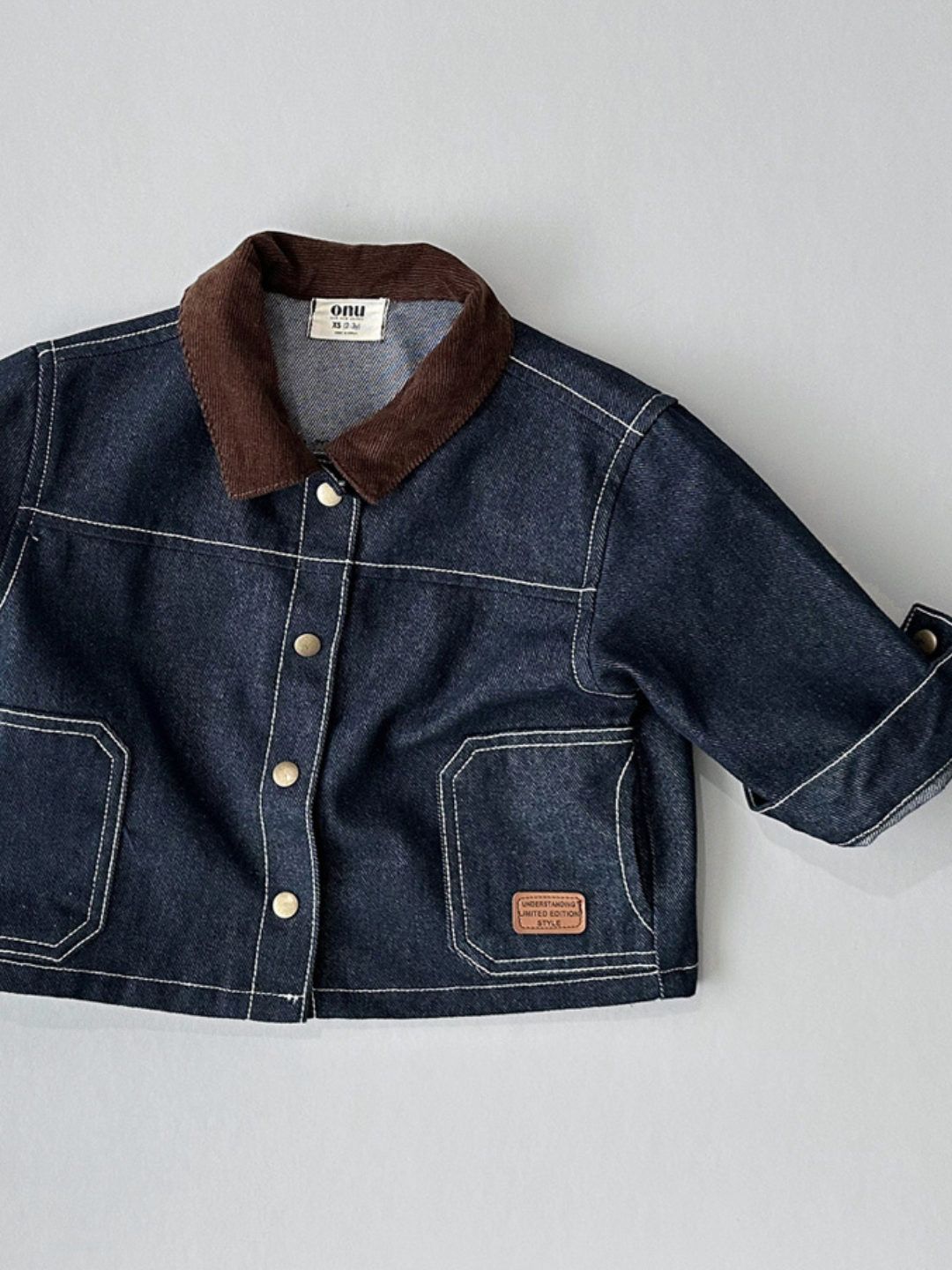 Indigo | Front view of kids indigo denim jacket with dark brown corduroy collar.