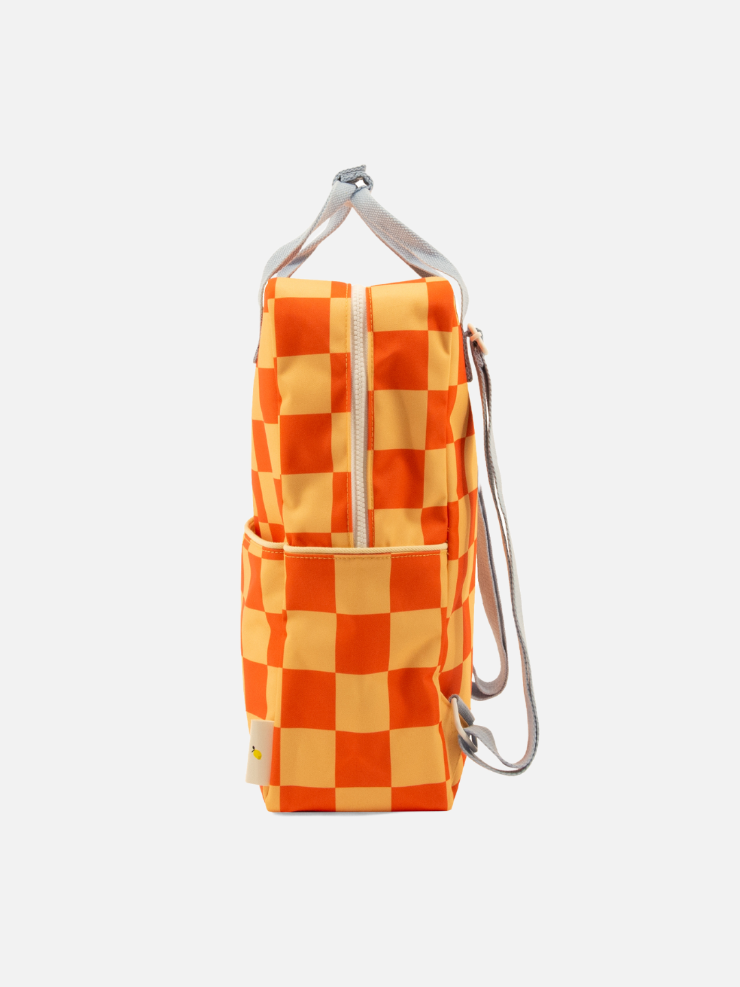 A side view of the LARGE FARMHOUSE CHECKERBOARD BACKPACK, showcasing an orange and cream pattern, front zipper, side pocket, light gray adjustable straps, and a waterproof lining made from recycled PET bottles.