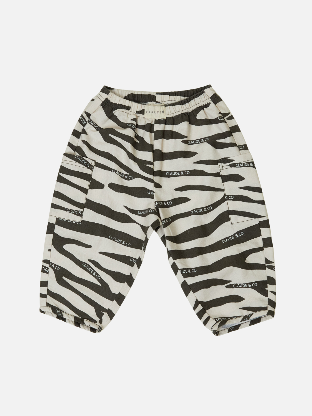 The EMERSON ZEBRA TROUSER features a black and white zebra pattern with an oversized silhouette, "Claude & Co" text print, and is crafted from organic cotton. It offers an elastic waistband and side pockets for comfort and style.