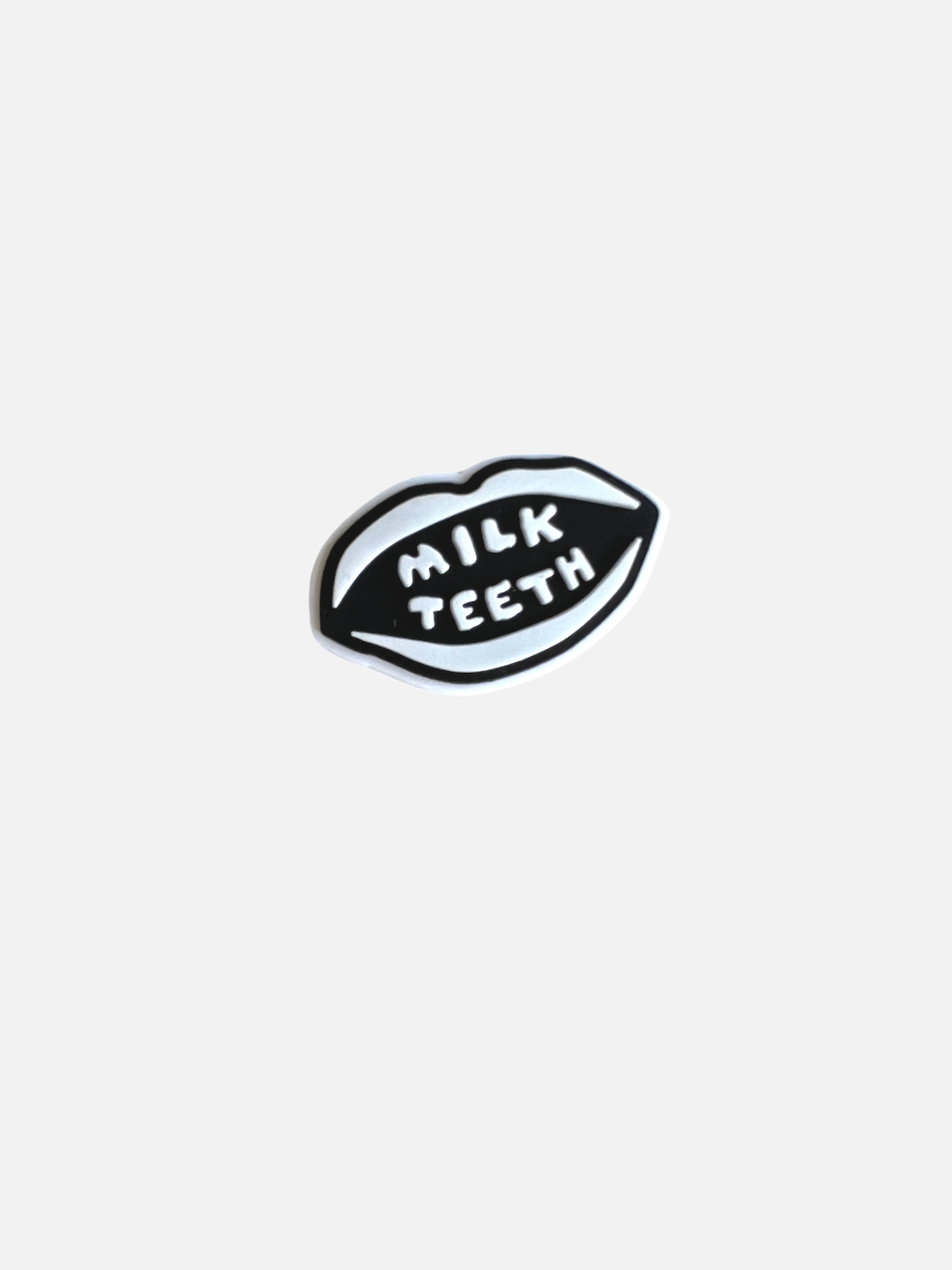 A rubber attachment for Crocs in the shape of the Milk Teeth logo