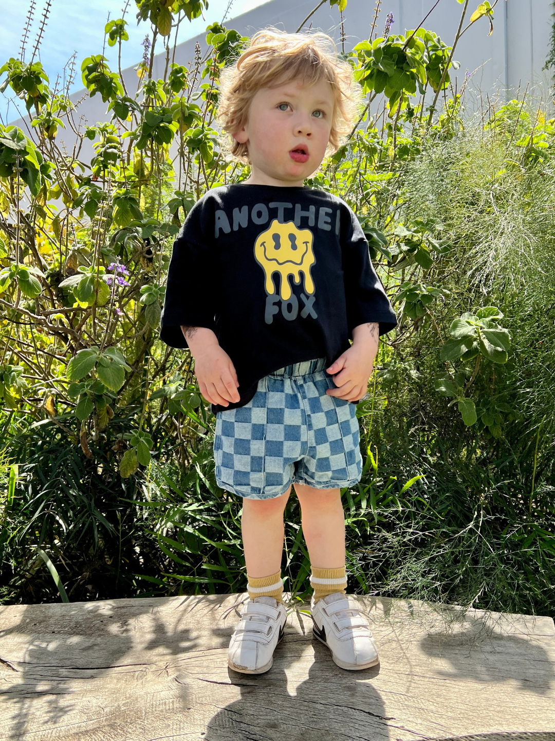A toddler wearing a pair of kids' checkerboard shorts in two shades of blue