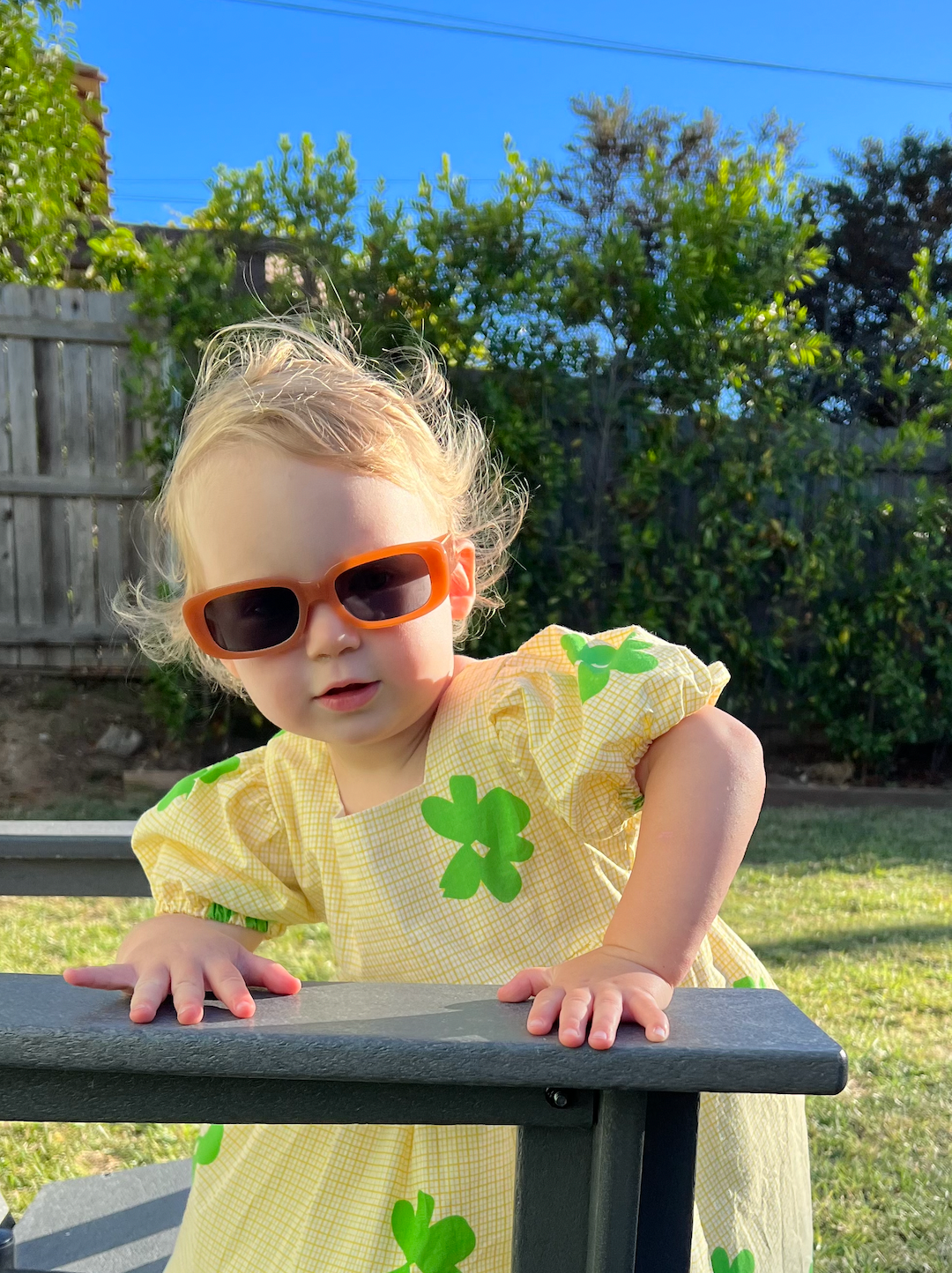 Black | A child wearing a pair of kids' sunglasses with orange frames and gray lenses