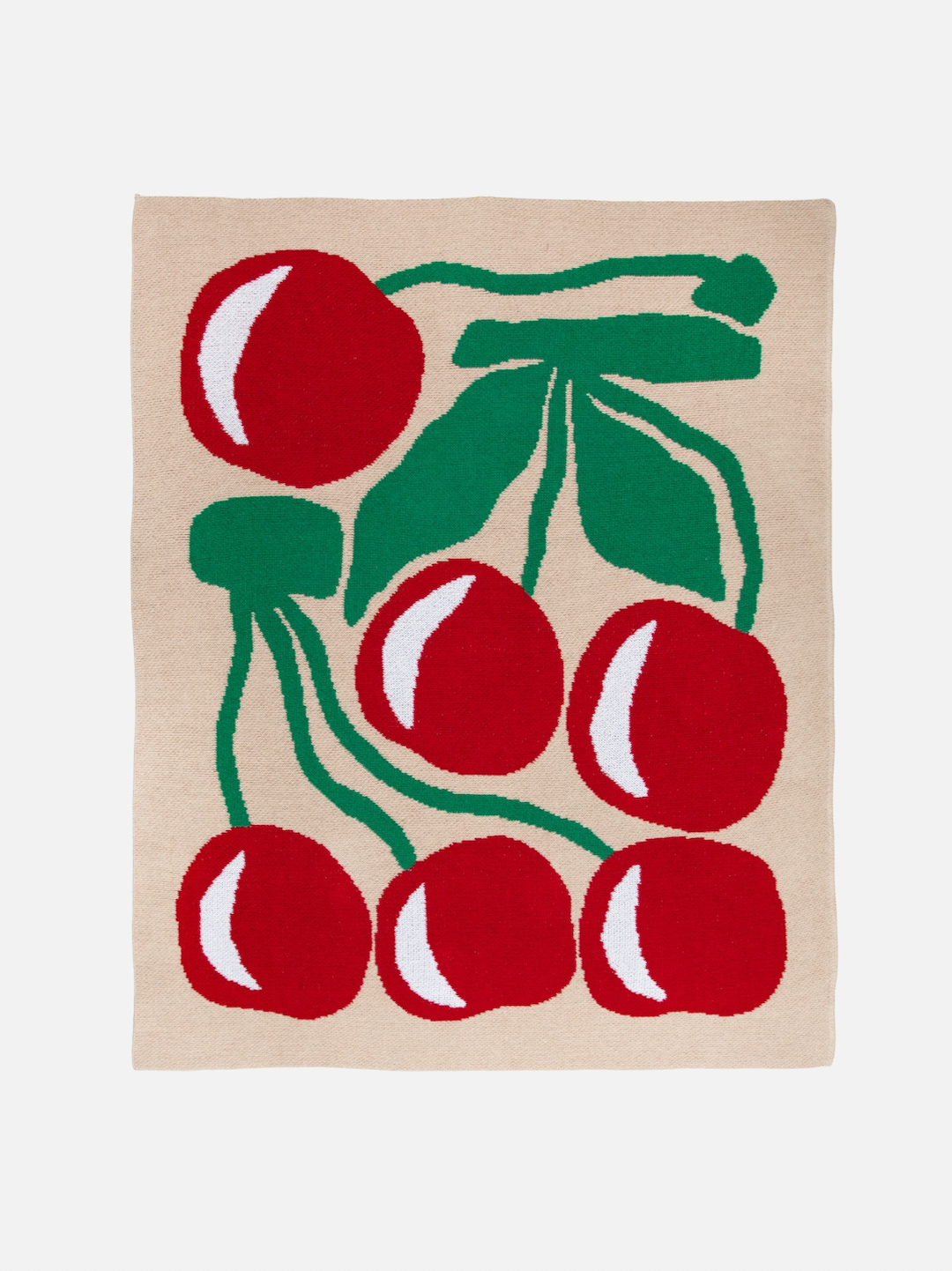 A mini blanket designed with red cherries and green leaves on a taupe background