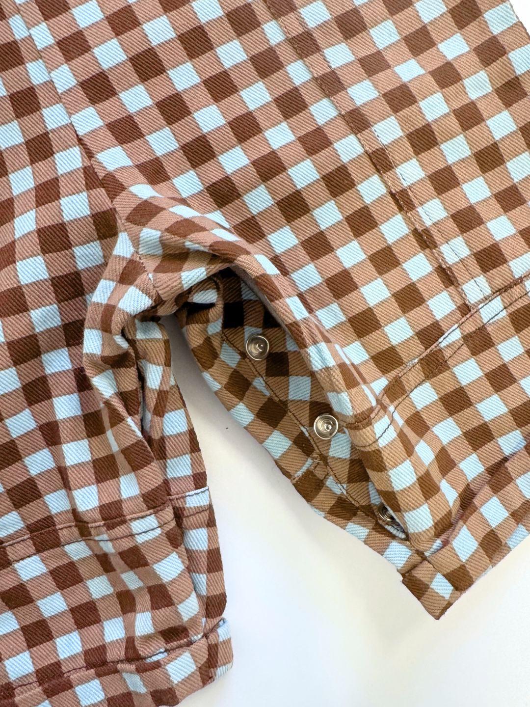 Brown and light blue checkered shirt with rolled-up sleeves on a white background
