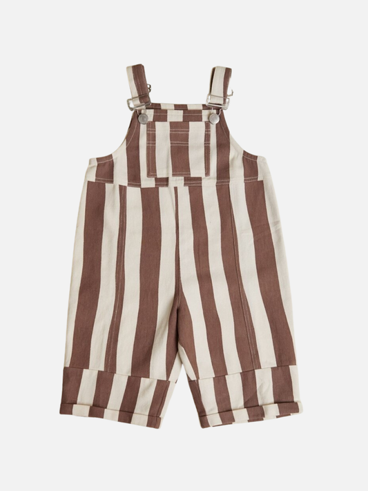 Image of The BLYTHE CHOC STRIPE DUNGAREE features wide vertical brown and white stripes, adjustable shoulder straps with metal fasteners, a front pocket, and cuffed hems for children.