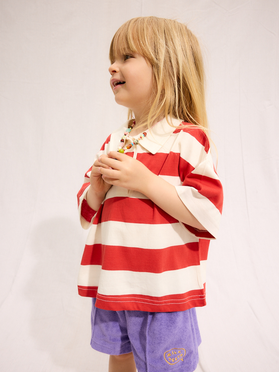 Purple | A child is wearing purple Everyday Terry Shorts with the Rugby Tee in Red