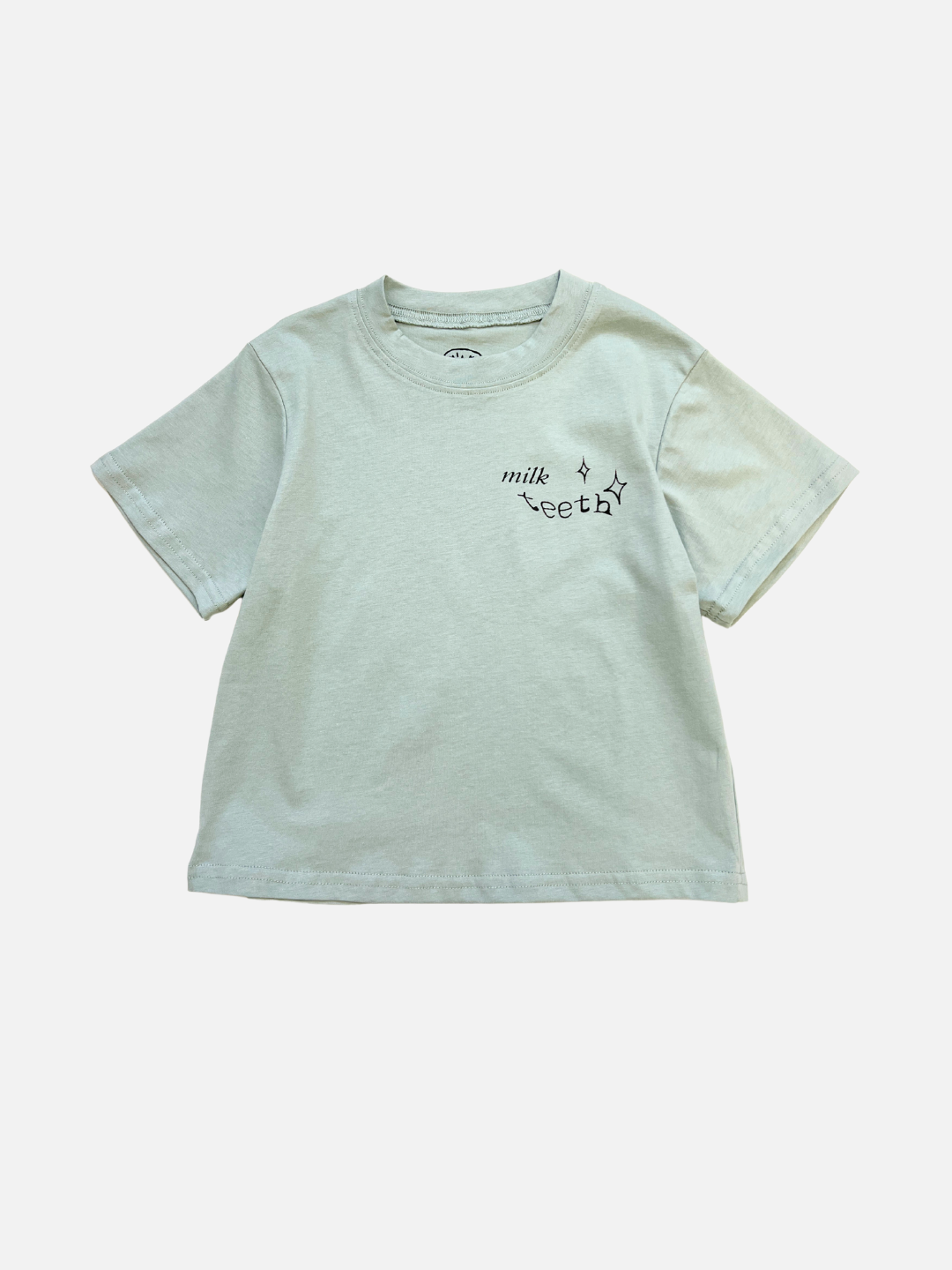 Mint | Mint short-sleeve MILK TEETH TEE featuring “milk teeth” and small star graphics, artist-designed and printed in black on the upper left chest.