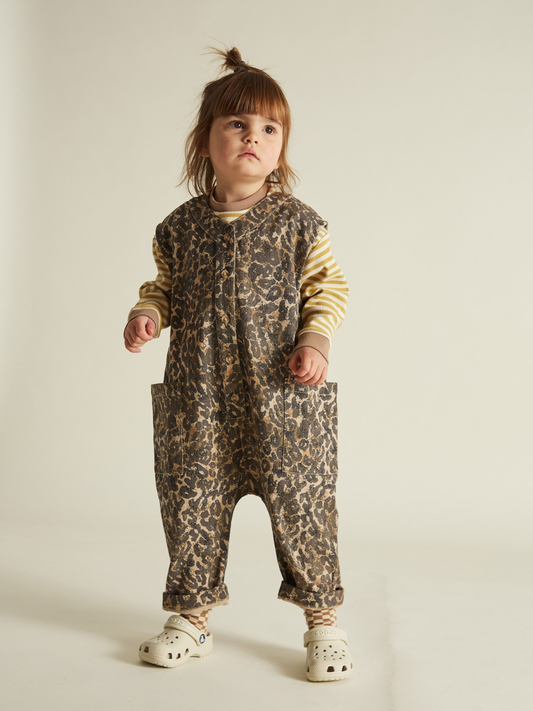 Second image of The WREN LEOPARD OVERSIZED OVERALL is an infant romper with a brown and black oversized leopard print. Crafted by a trusted British brand from soft organic cotton, this unisex piece includes two front pockets and a convenient snap closure for easy dressing.