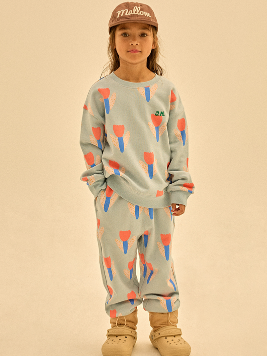 Second image of The TULIP SWEATSHIRT is a light blue top with a repeating pink and blue tulip-like floral pattern, offering stylish comfort —shown laid flat on a white background.