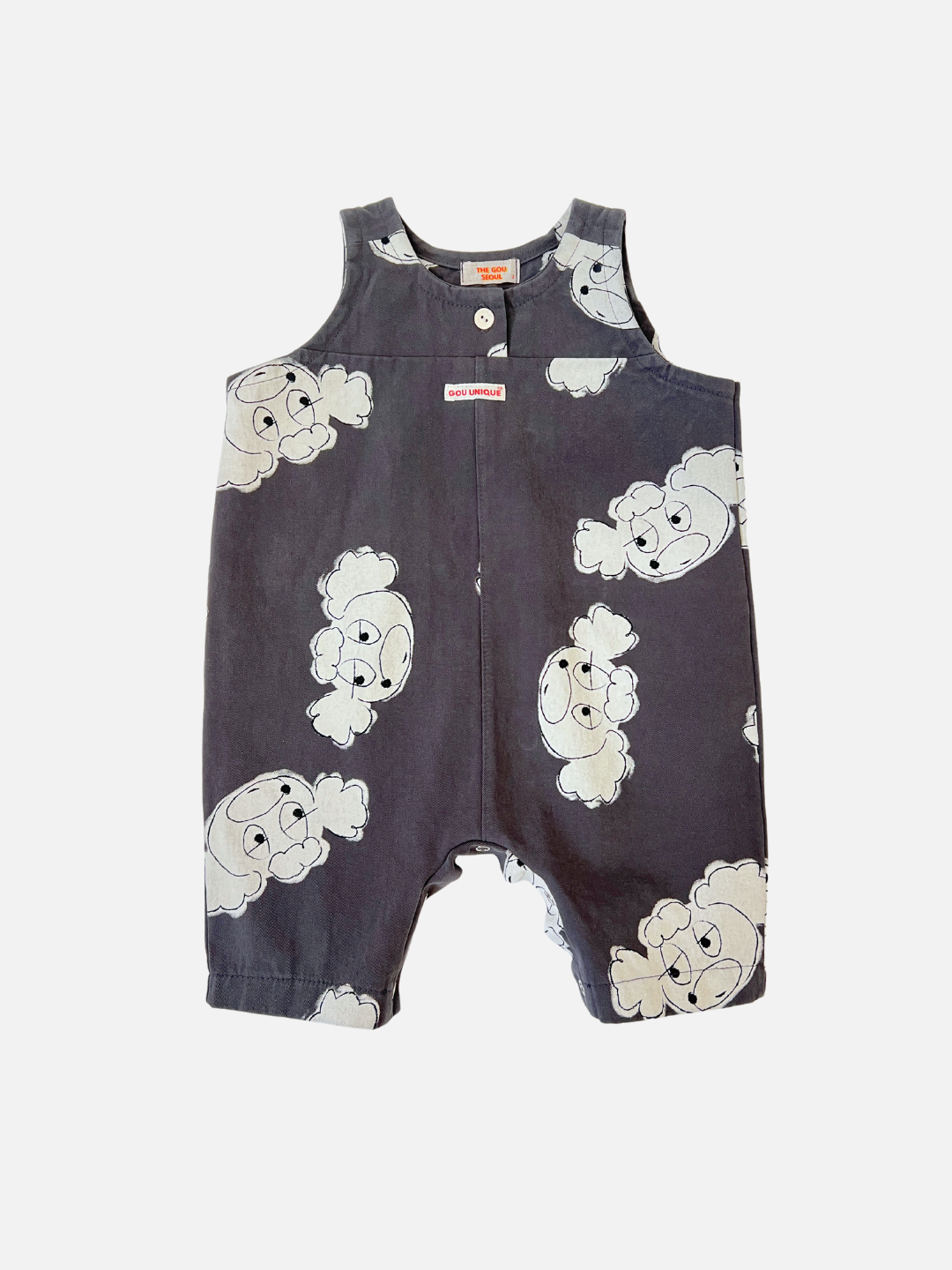 The POODLE OVERALL is a dark blue romper by a Korean kids' label, featuring a white cartoon ghost pattern. It includes shoulder straps and a front button, ideal for playful adventures.