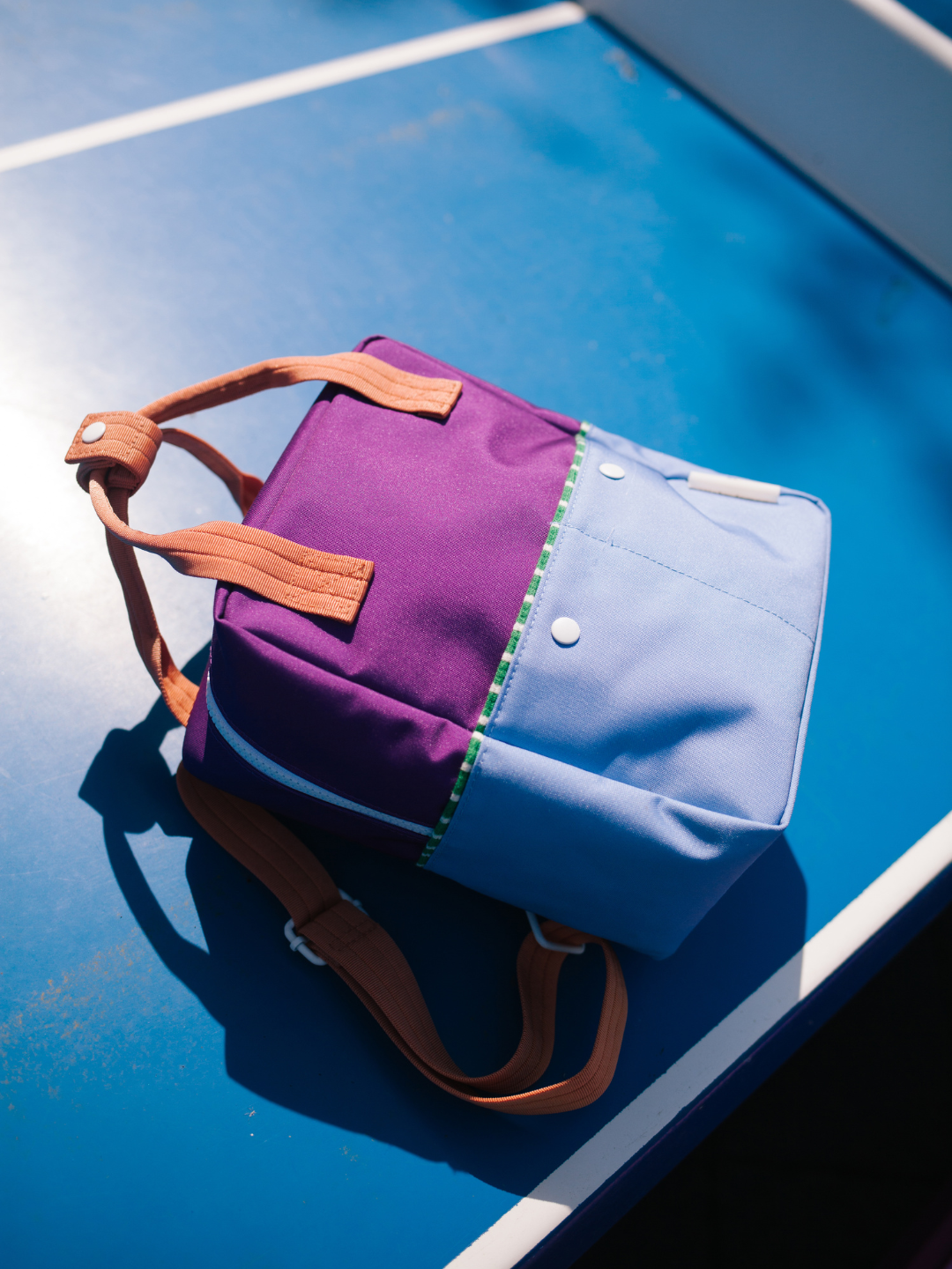 Purple Tights | A kids' Colourblock backpack in purple tights is laid flat on a ping pong table. 