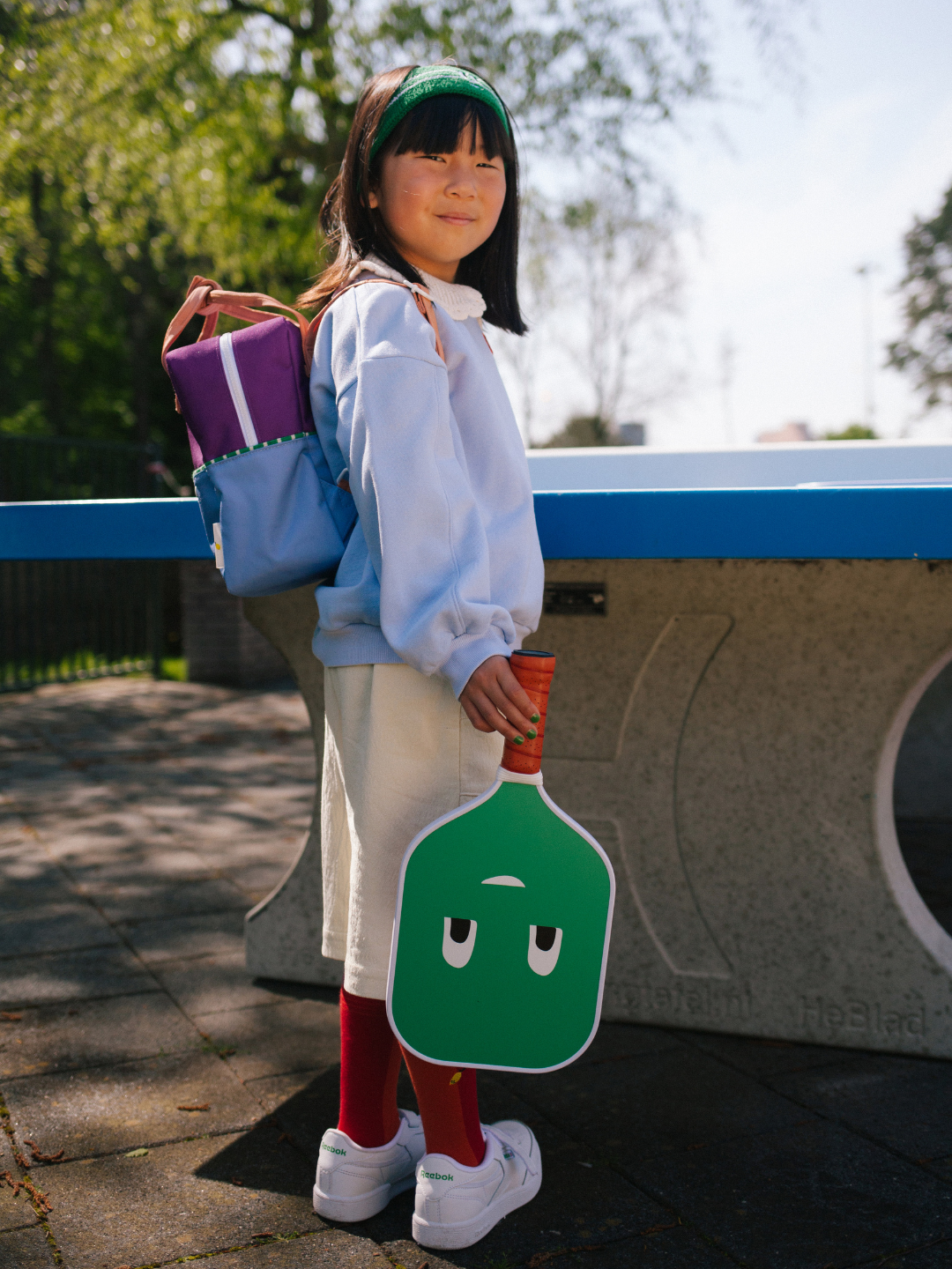 Purple Tights | A child is wearing the Coulorblocking backpack in Purple Tights while holding a pickleball racket