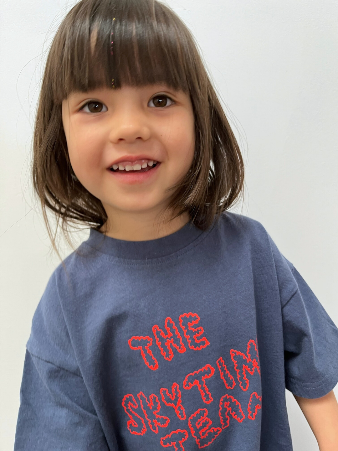 Child wearing a blue shirt with red text against a white background