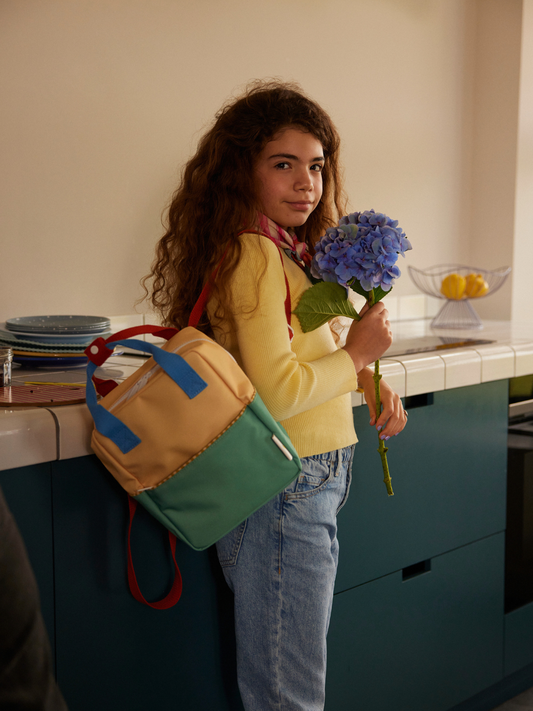 Second image of Sandy Yellow/Aquatic Green | The SMALL COLOURBLOCKING BACKPACK, made from recycled PET bottles, features a sandy yellow top, aquatic green bottom, blue handles, red snap closure, and waterproof lining—shown against a plain white background.
