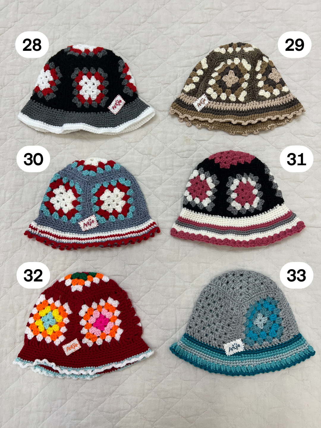 A handmade CROCHETED BUCKET HAT 1-3Y (Copy) in color #28 with a unique pattern and white "AOK" tag lies on a quilted surface, inspired by the vibrant style of South Africa.